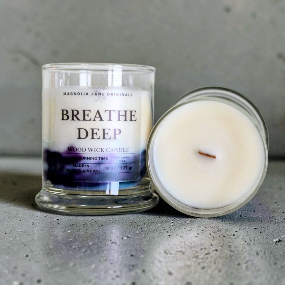 Breathe Deep is a wooden wick candle that is a creamy white color with a swirl design on the lower half of the candle in teal & purple