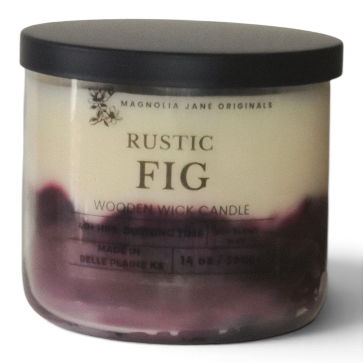 A 14 oz jar candle by Magnolia Jane Originals in the scent Rustic Fig. The candle features a black lid, a cream-colored wax body with a dark purple bottom layer, and a clear glass container.