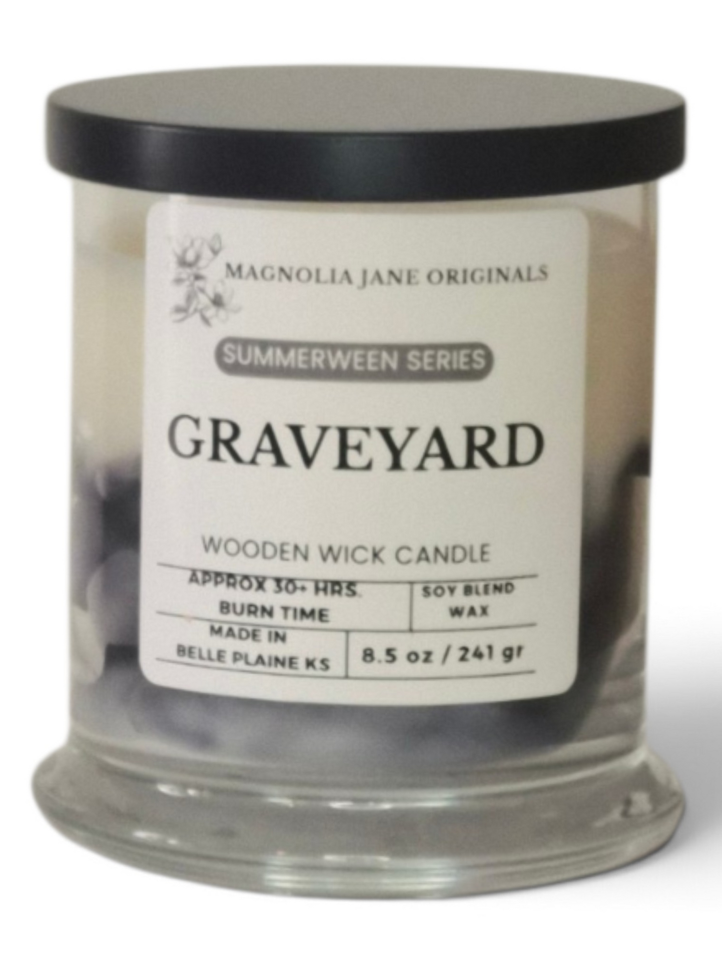 A Magnolia Jane Originals 'Graveyard' wooden wick candle in a clear glass jar with a black lid and a white label, set against a plain white background.