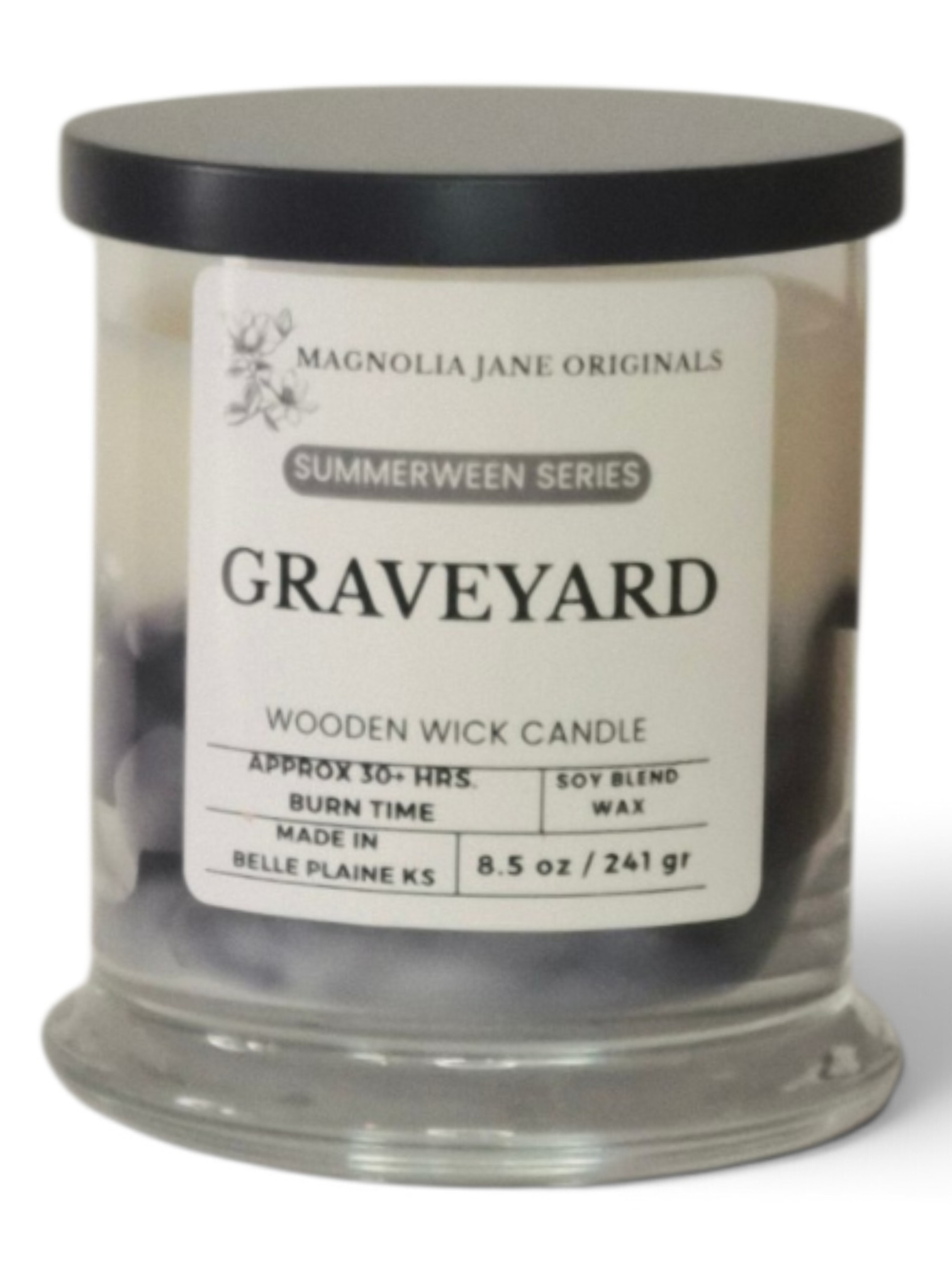 A Magnolia Jane Originals 'Graveyard' wooden wick candle in a clear glass jar with a black lid and a white label, set against a plain white background.