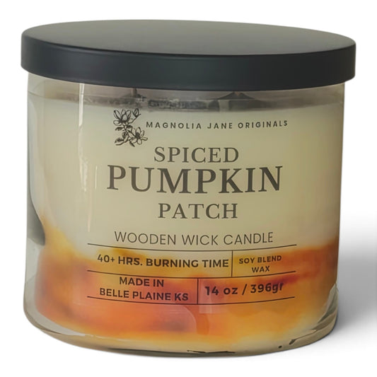 A 14 oz glass jar candle by Magnolia Jane Originals in the 'Spiced Pumpkin Patch' scent, featuring a black lid and a label with orange and yellow accents on a white background.