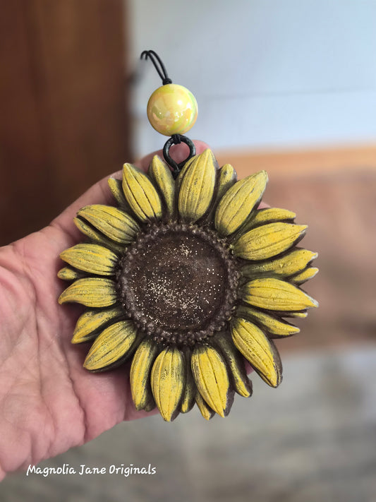 Sunflower-shaped air freshener for any type of vehicle held in a hand with a blurred background