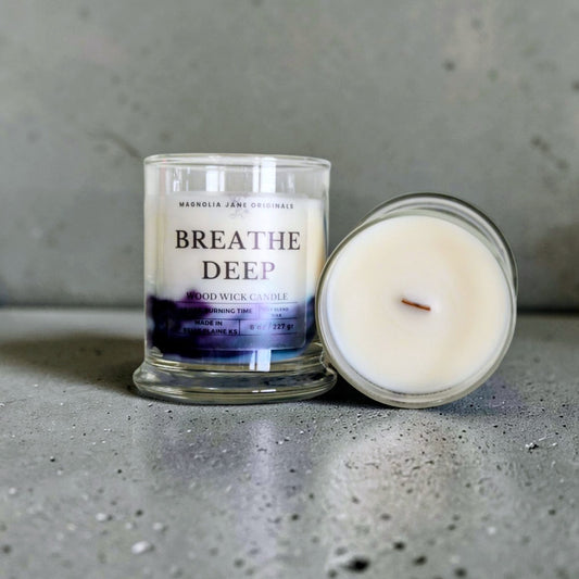 Breathe Deep  is a wooden wick candle that is a creamy white color with a swirl design on the lower half of the candle in teal & purple