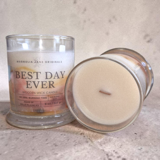 Candle with 'Best Day Ever' label and wooden wick on a neutral background
