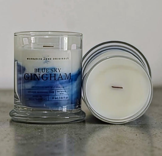 Candle with a visible label titled 'Blue Sky Gingham' on a neutral background