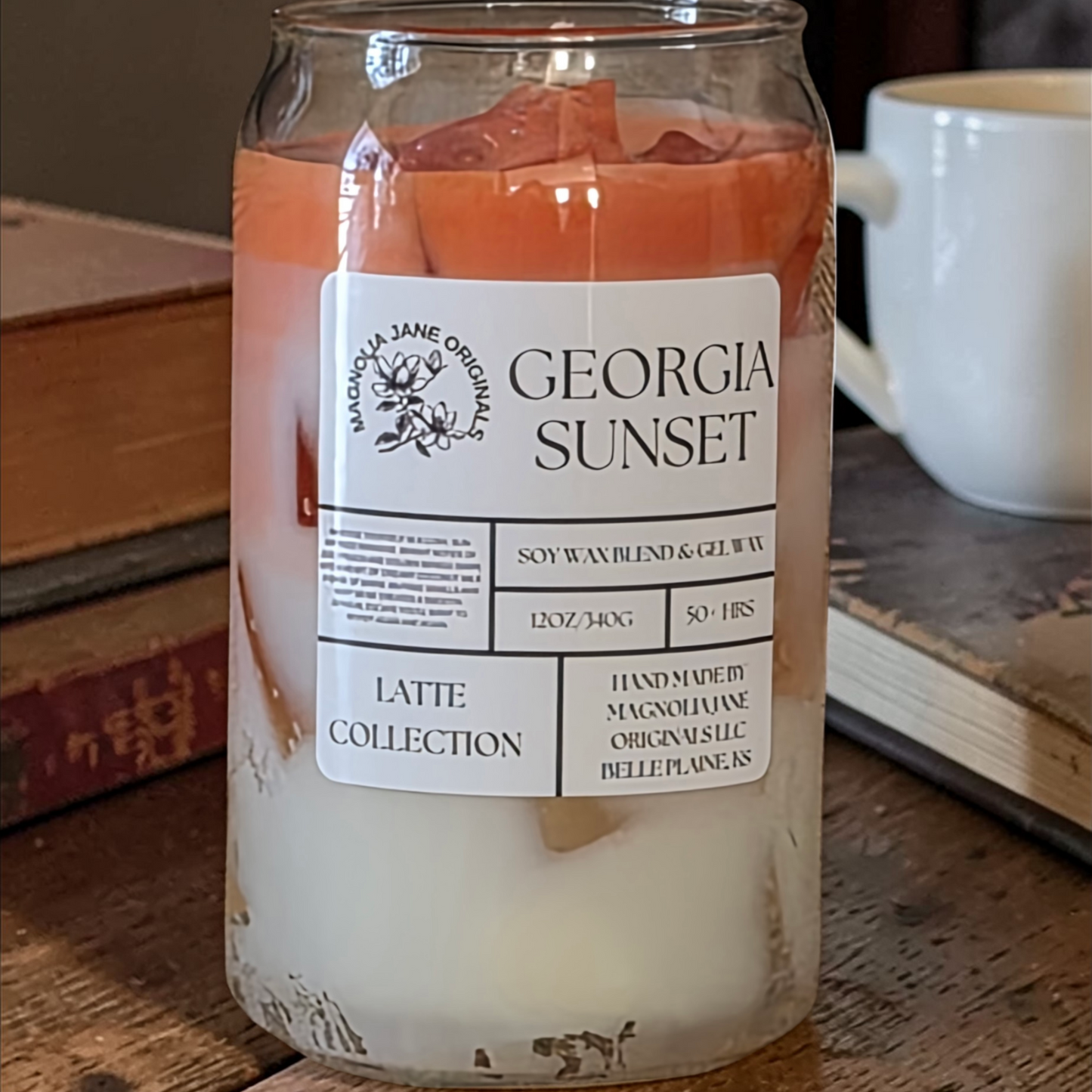 A tall glass with gel wax that appear to look like ice cubes.  The cubes glow when lit. The top third of the candle is a burnt orange and the bottom 2/3 is a creamy white with a blend where they meet.