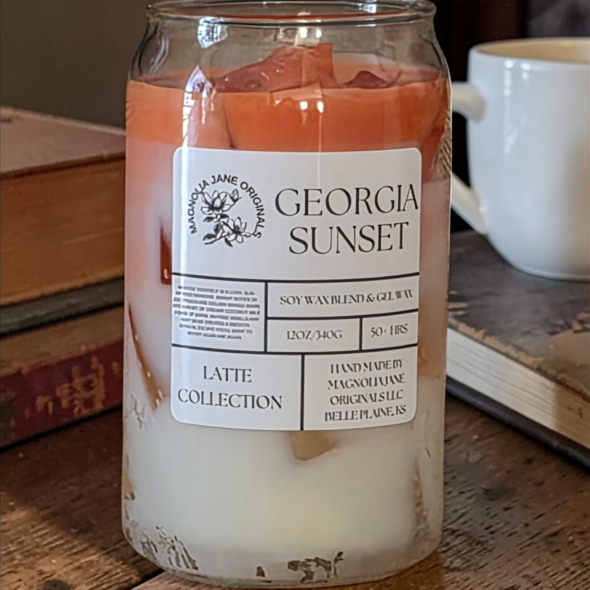 A tall glass with gel wax that appear to look like ice cubes.  The cubes glow when lit. The top third of the candle is a burnt orange and the bottom 2/3 is a creamy white with a blend where they meet.