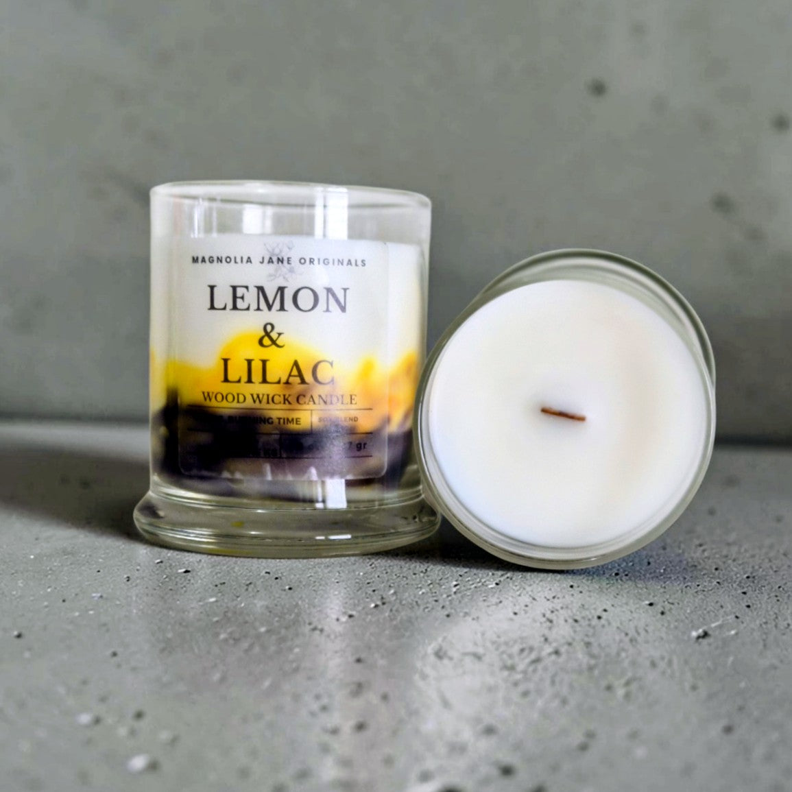 Lemon & Lilac is a wooden wick candle that is a creamy white color with a swirl design on the lower half of the candle in yellow & purple