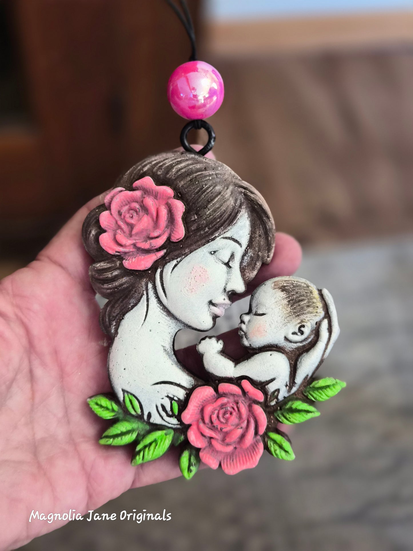 Mother & Baby  with pink roses & green leaves air freshener for any type of vehicle held in a hand with a blurred background