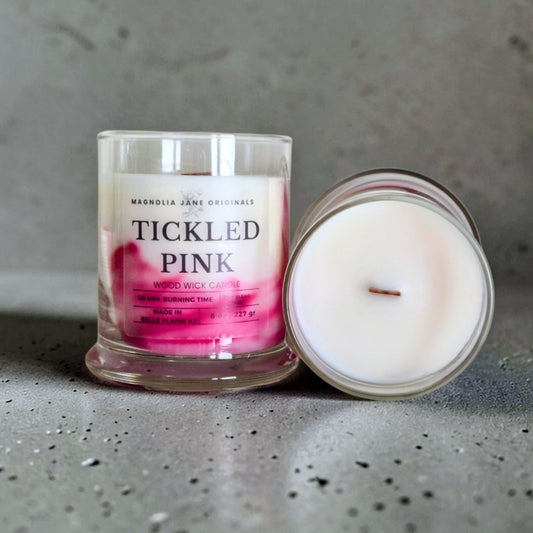 Tickled Pink is a wooden wick candle that is a creamy white color with a swirl design on the lower half of the candle in shades of pink.