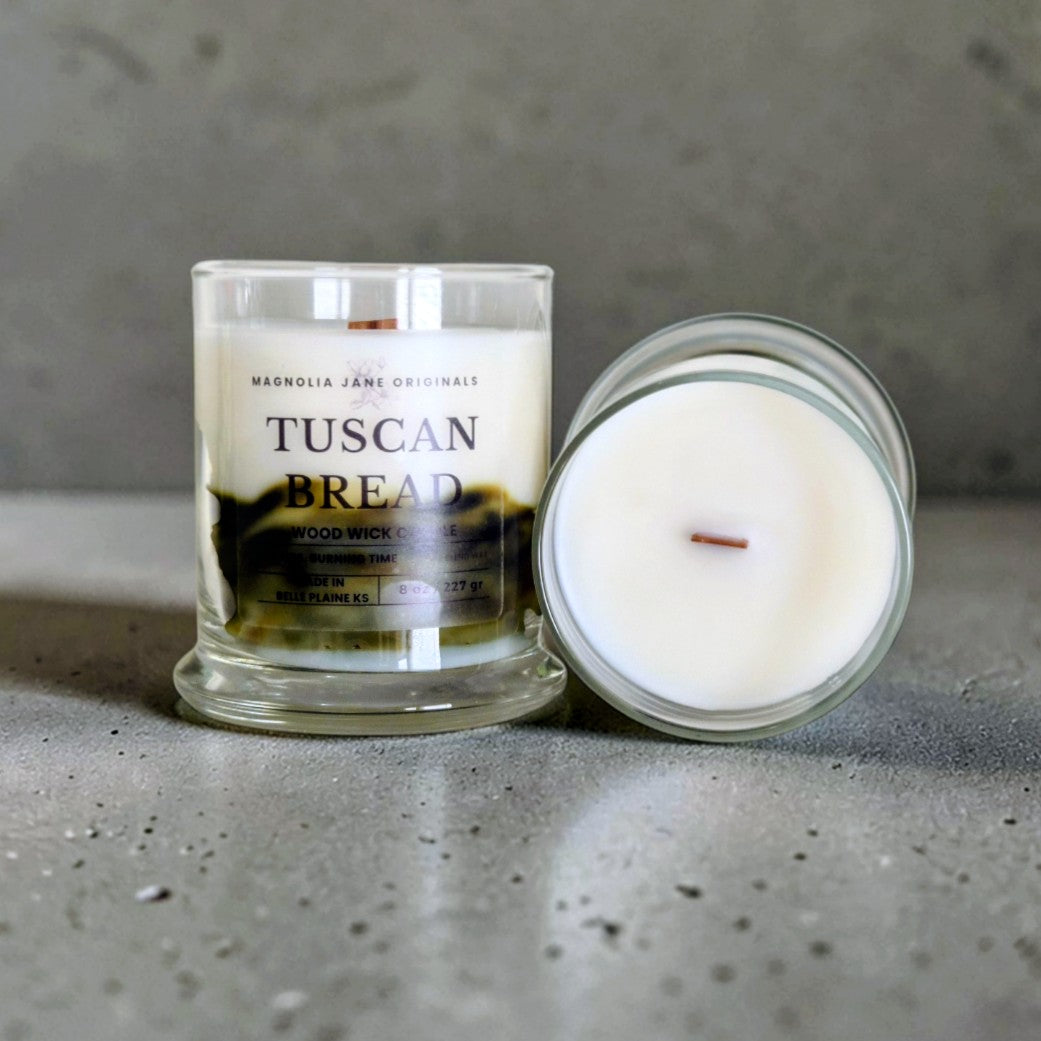 Tuscan Bread is a wooden wick candle that is a creamy white color with a swirl design on the lower half of the candle in brown & olive green